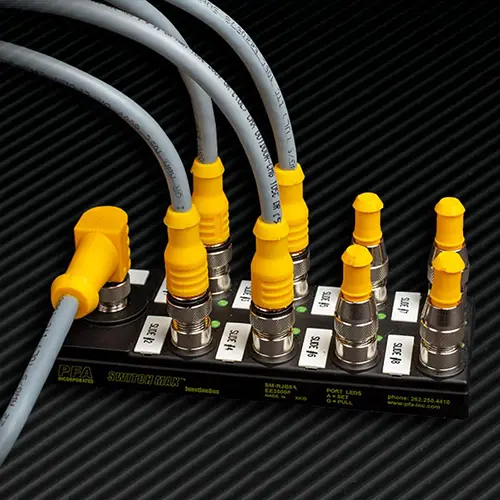 Multiple grey cables with yellow connectors plugged into a SWITCHMAX™ Package System