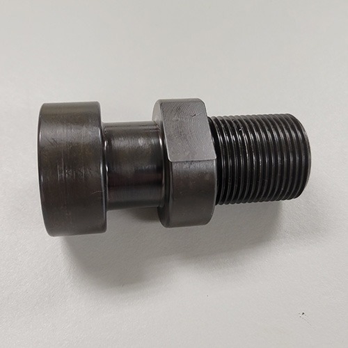 A metal assembly consisting of a large bolt, two washers, and a black rubber element, possibly a vibration damper, on a grey surface.