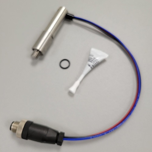 A blurred image of an industrial sensor with a black and blue cable, a metal cylindrical part, a small rubber O-ring, and a tube of white thread sealant.