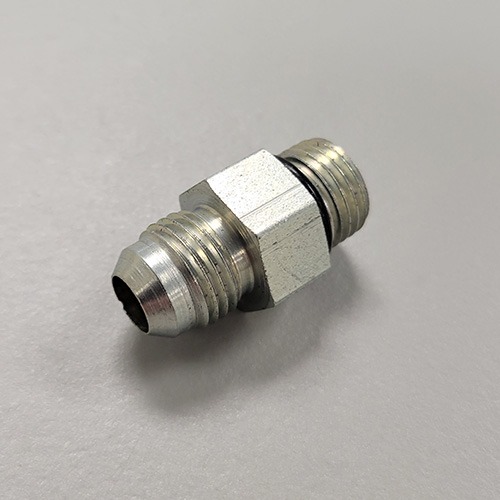 A hydraulic fitting with male threads on both ends and a hexagonal nut in the middle, made of metal, on a white surface.